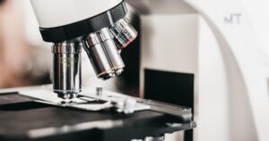 A Meiji Techno microscope with multiple objective lenses above a black stage